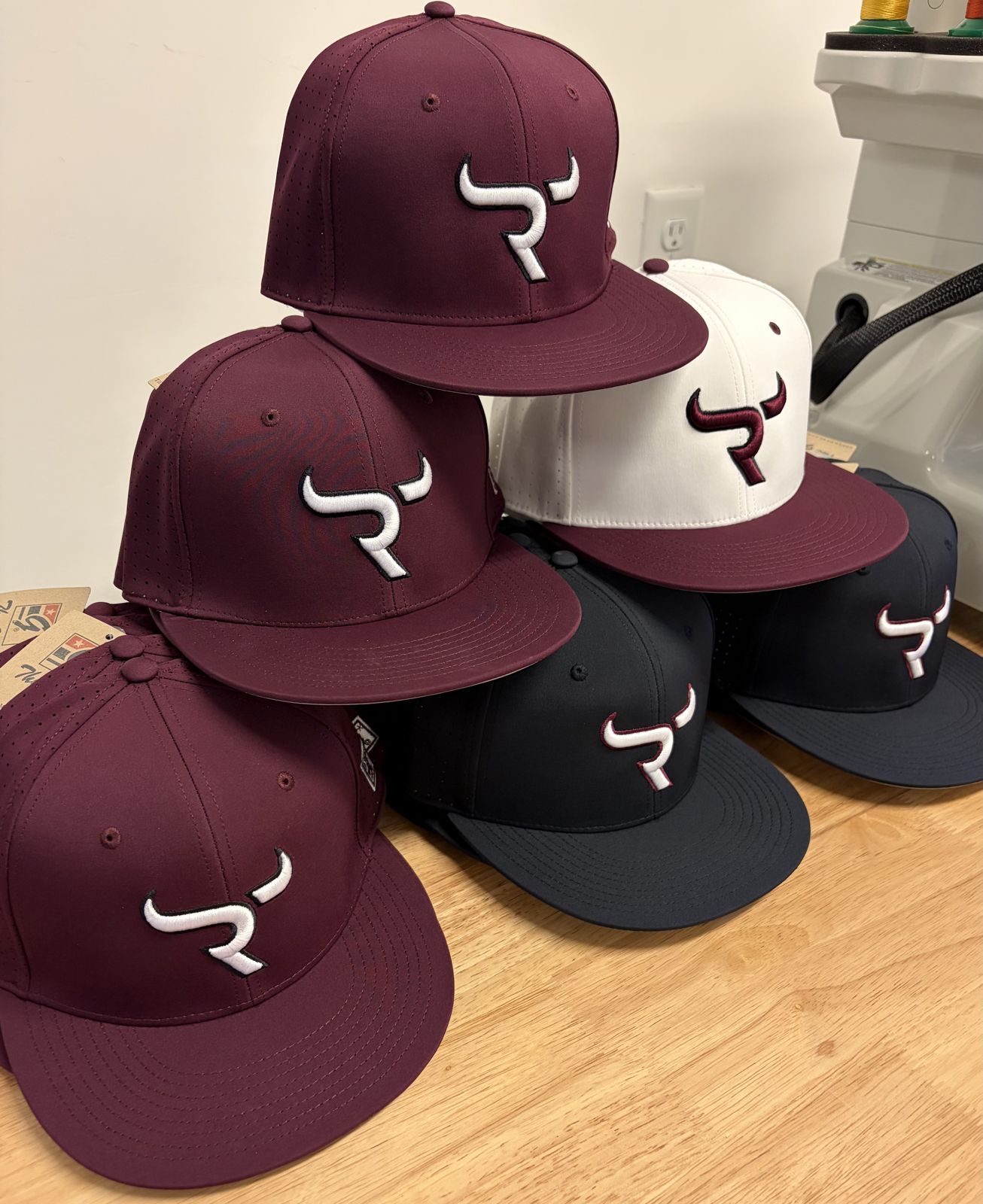 Maroon, white and navy fitted caps with a 3D puff bull-horn R logo