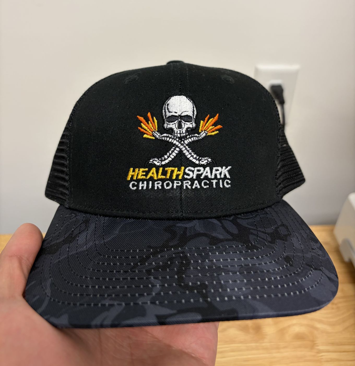 Black trucker cap with a detailed multi-color logo