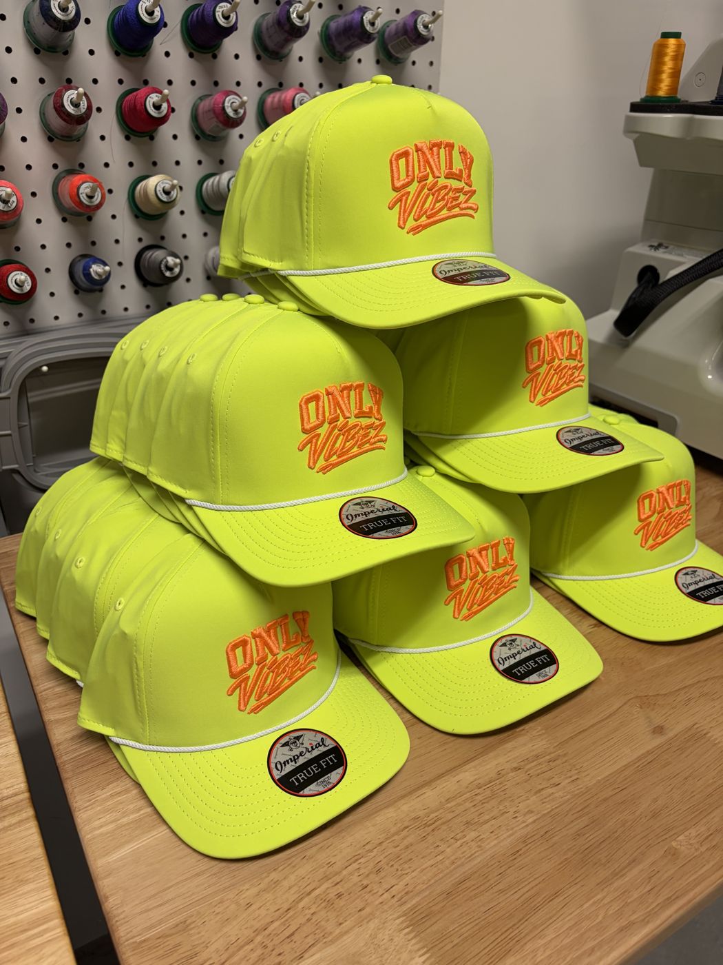 Stack of neon yellow rope hats with orange 3D puff lettering