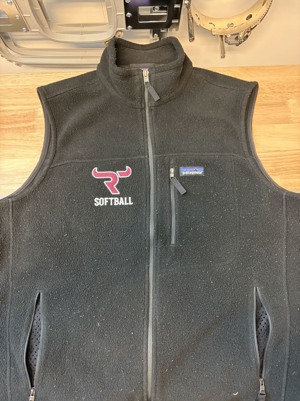 Black fleece vest with an embroidered softball logo