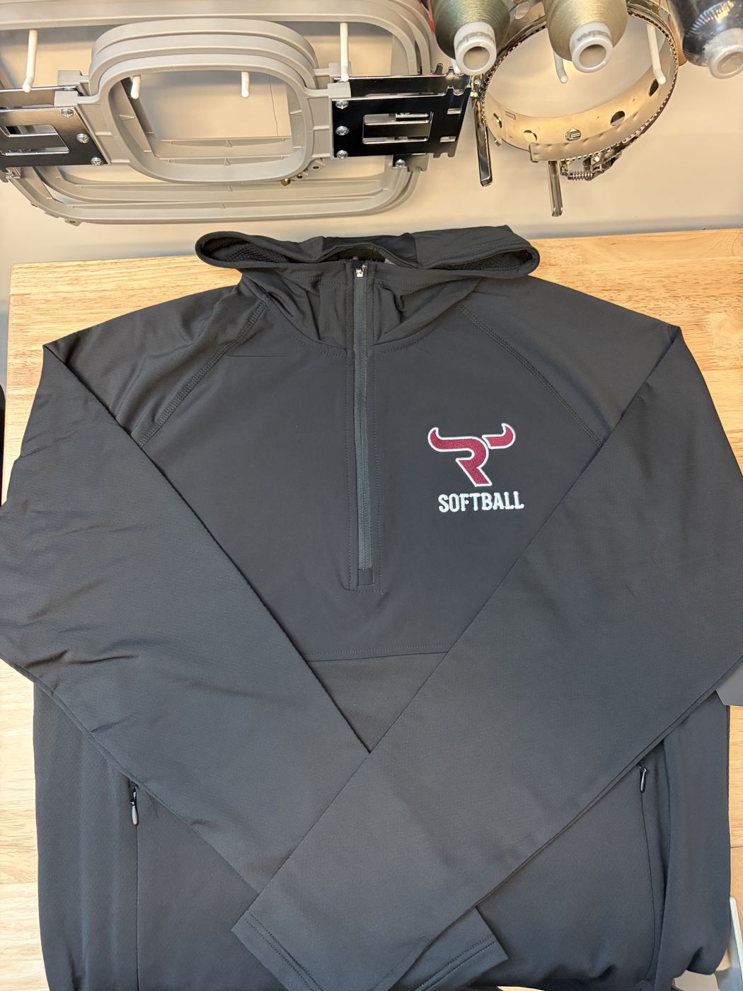 Black quarter-zip hoodie with an embroidered softball logo
