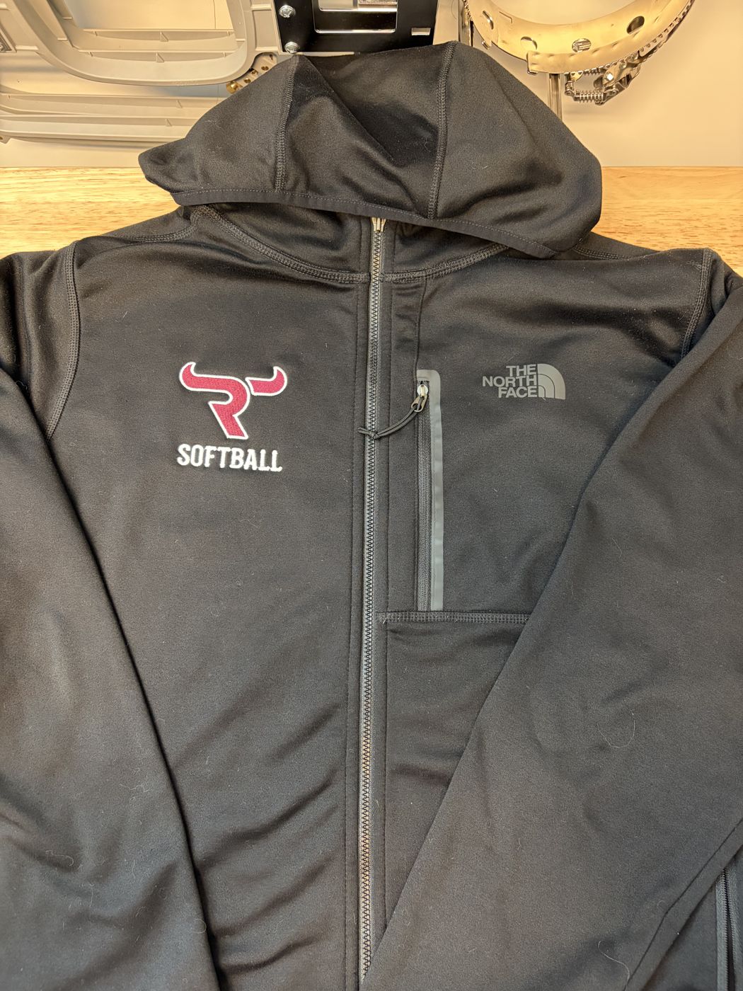 Black zip hoodie with an embroidered softball logo