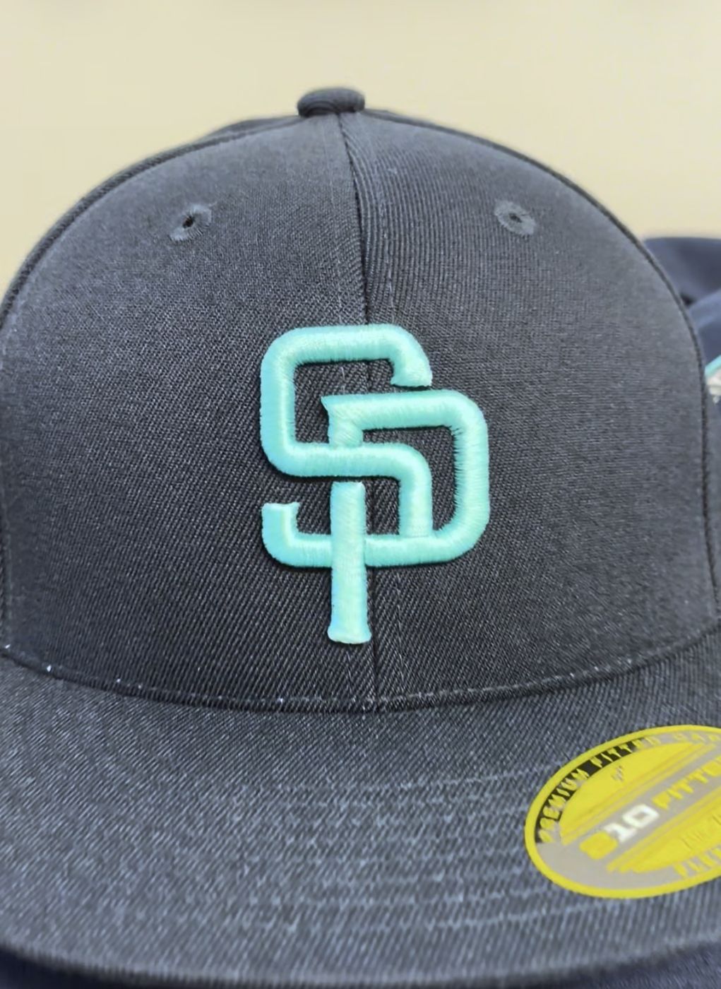 Navy fitted team cap with a 3D puff embroidered teal SP logo