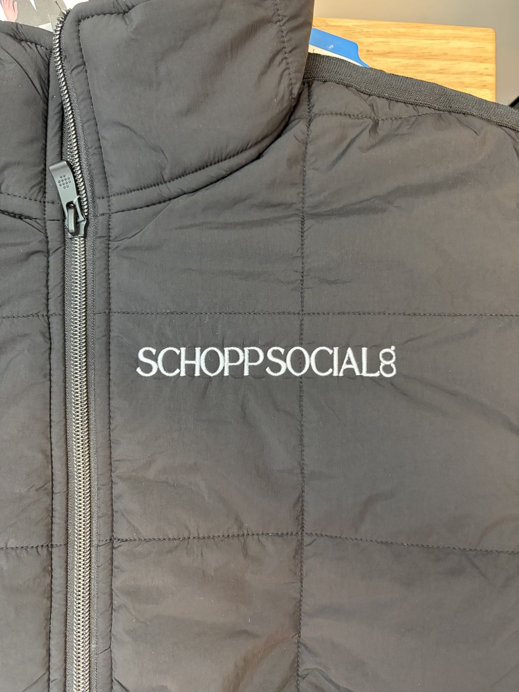 Black quilted vest with a clean white wordmark